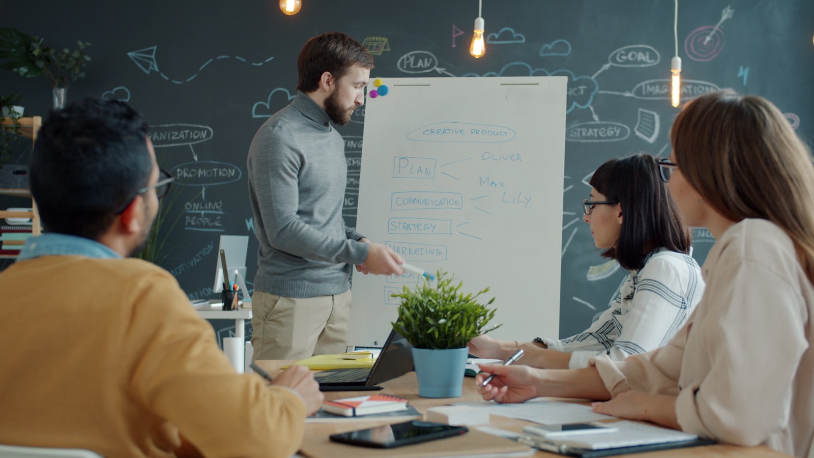 A team collaborates around a whiteboard, mapping out an accreditation preparation timeline in a modern office.