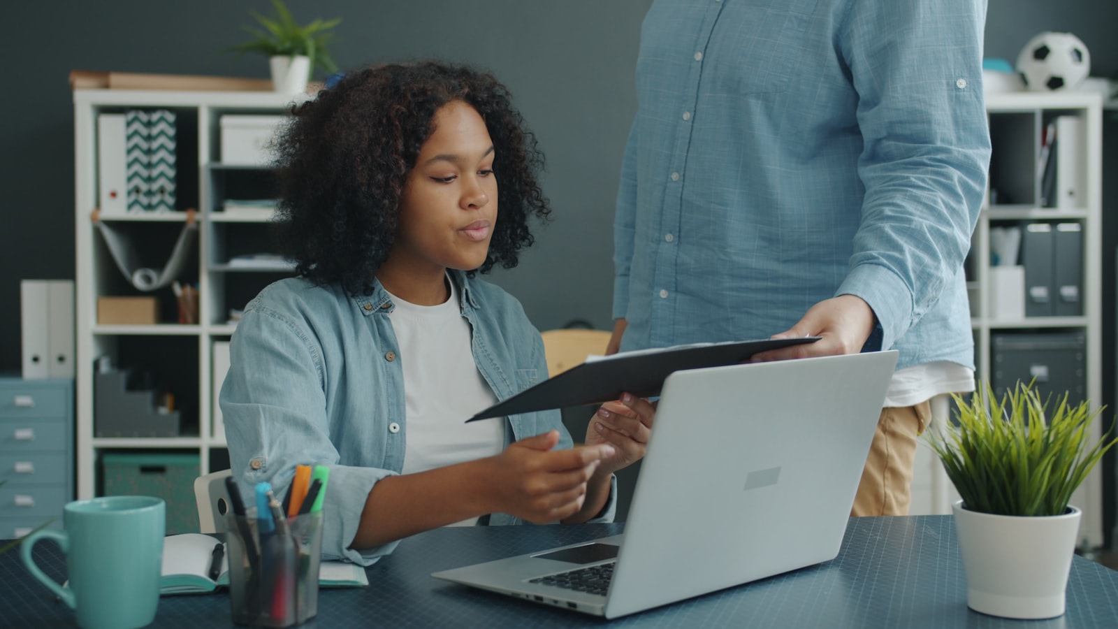 Two colleagues review compliance documents together at an office desk.