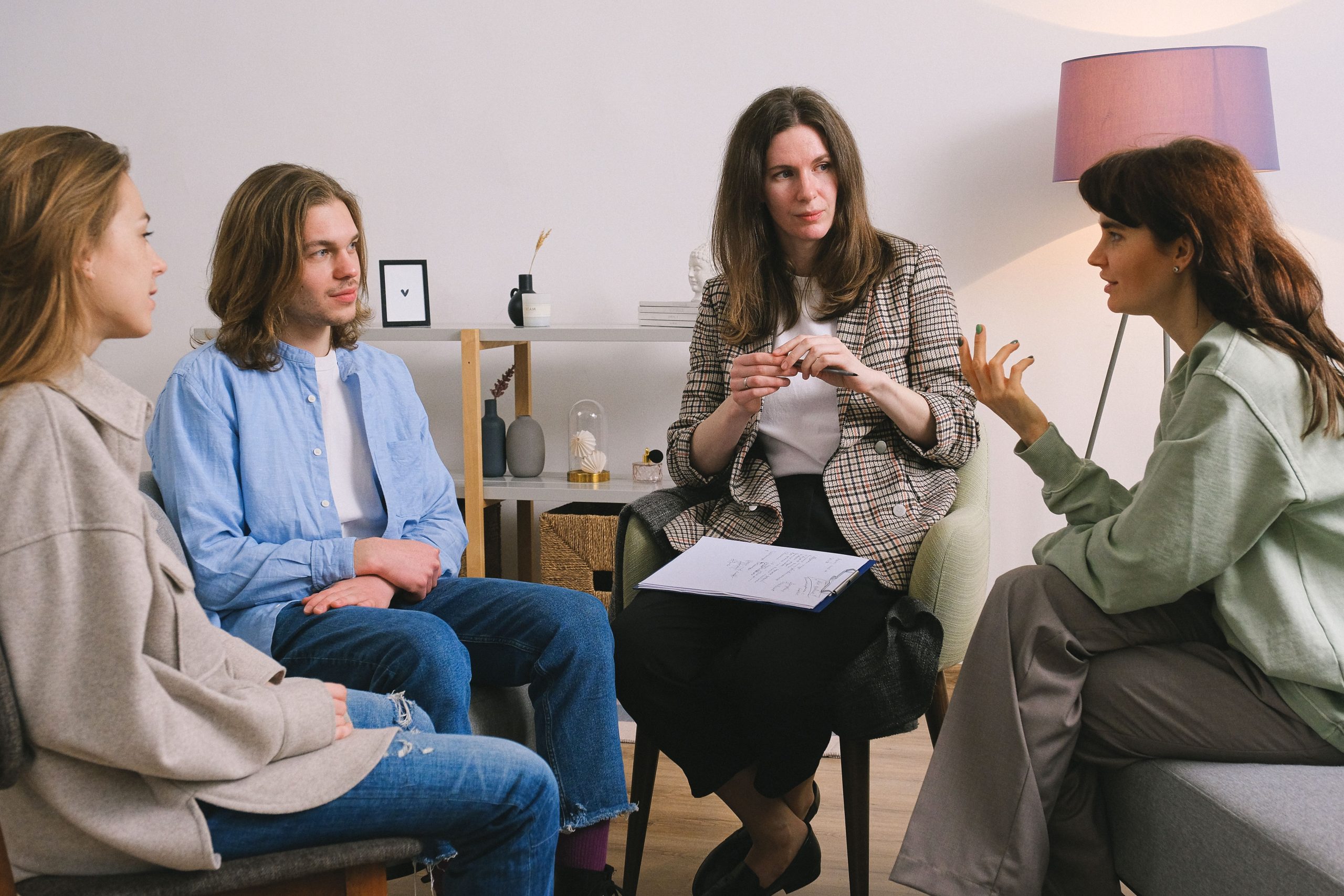 A counselor leads a group therapy session with clients seated together in a treatment program