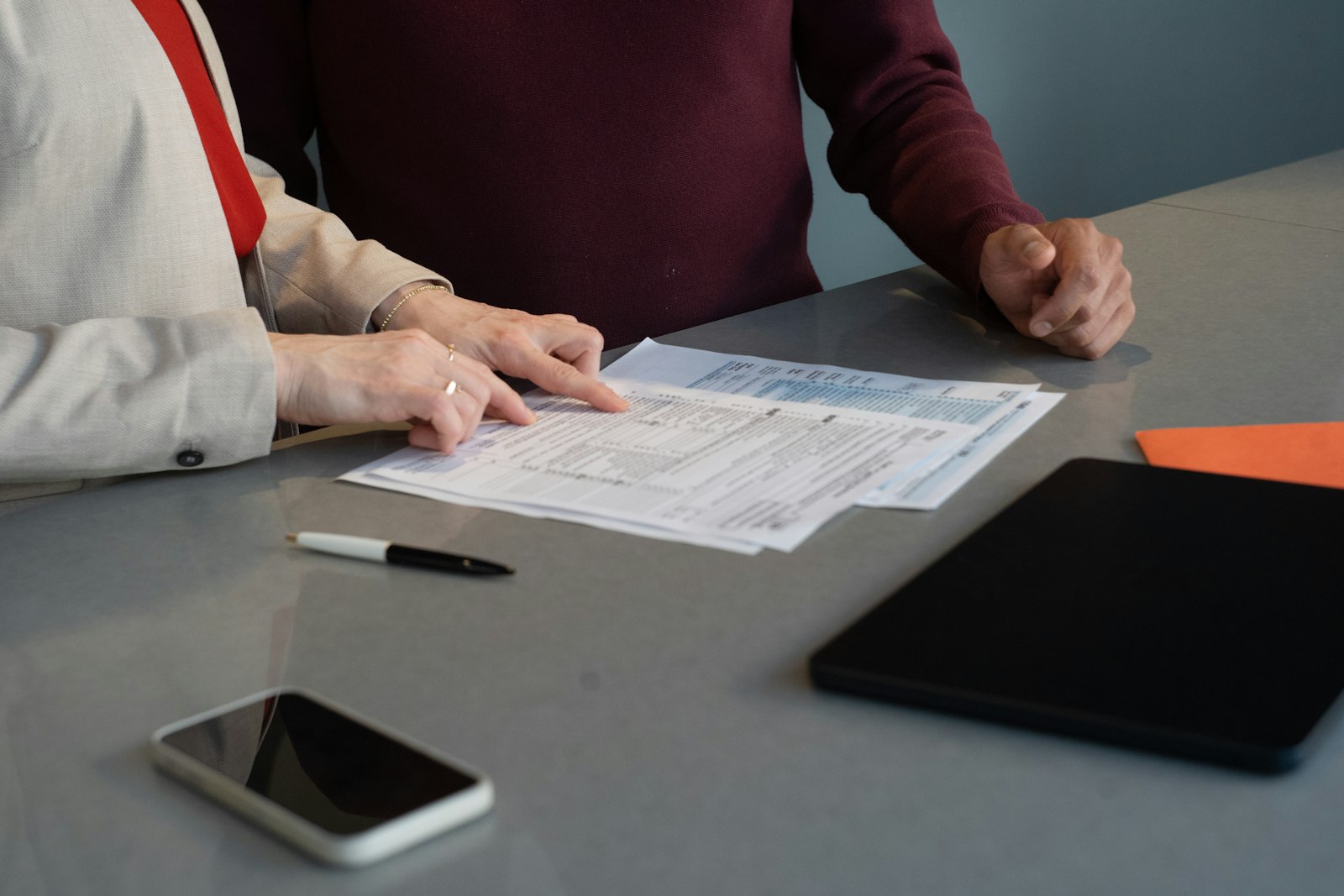 Two people review program documents together at a table, checking them while they review CARF survey findings.