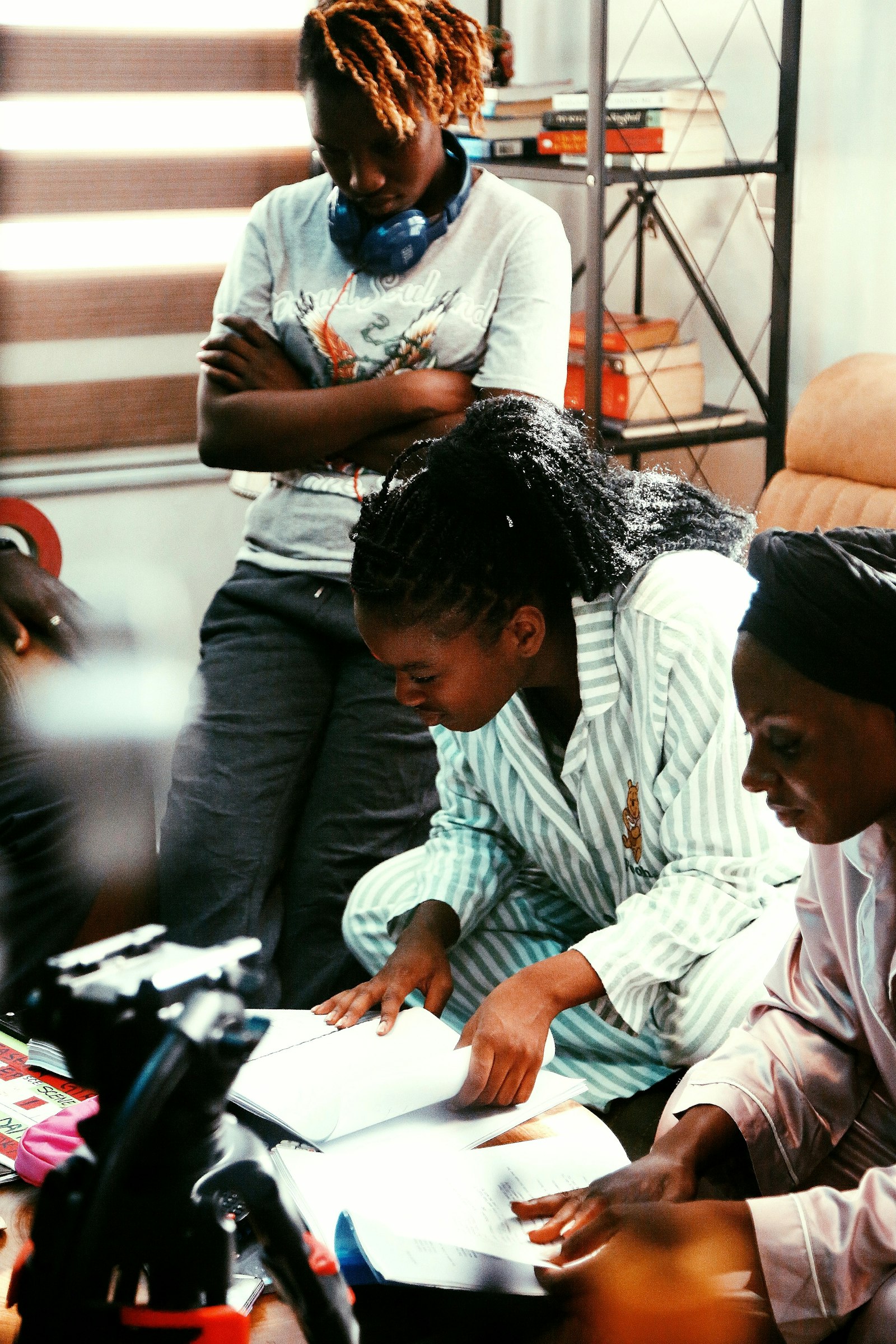 Three women review printed program records together at a table during an internal compliance check.
